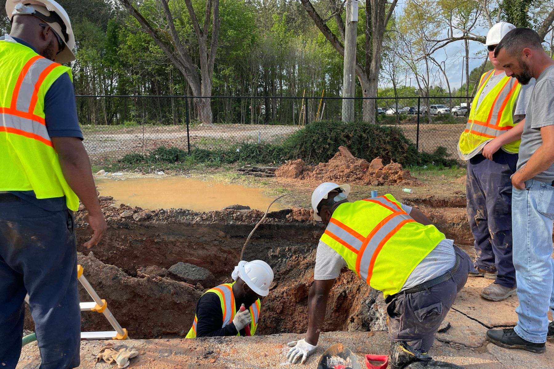 Water line repair Lebanon OR: a crew working in an excavation beside the street to reach a service line