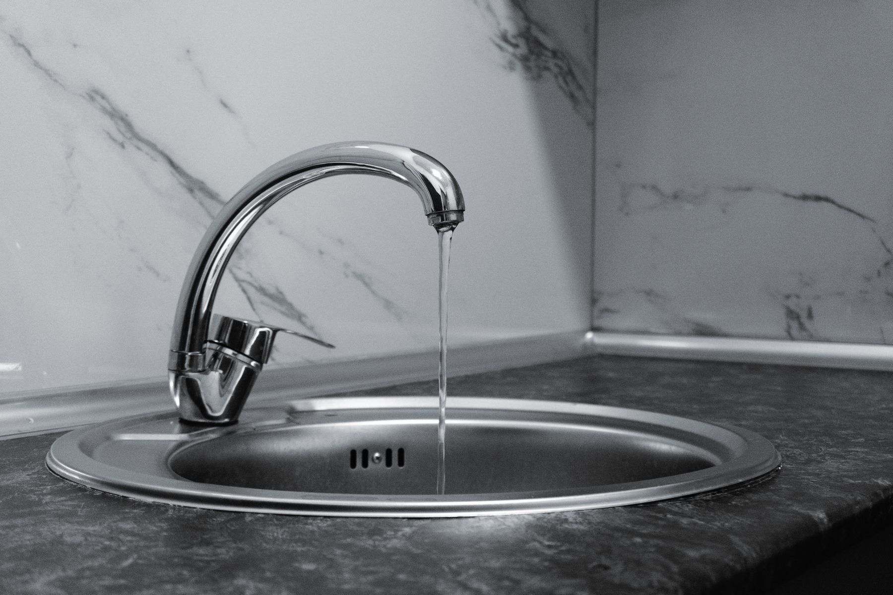 Kitchen faucet running into a steel sink, where cloudy or discolored water first shows a Millersburg Oregon water line problem