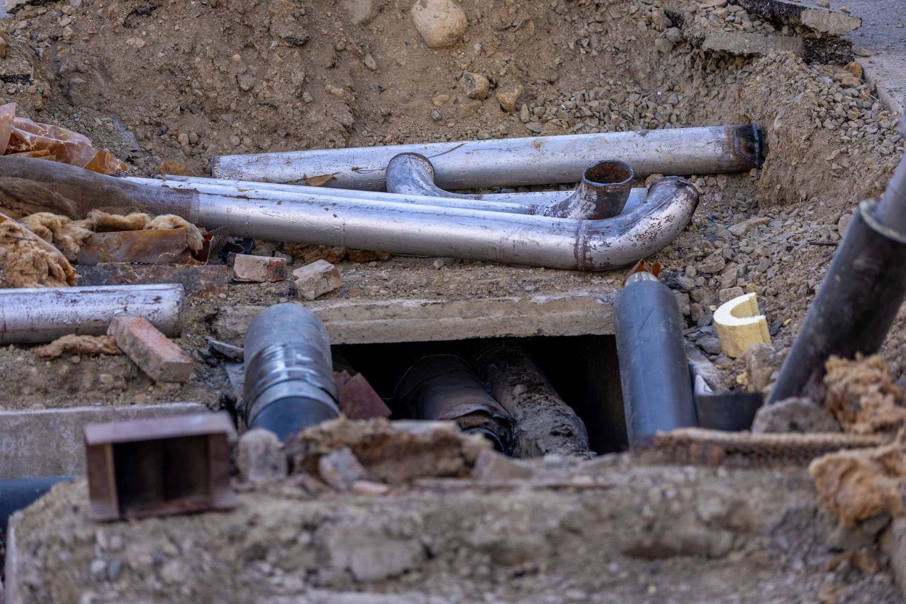 Old pipes exposed in an excavated pit, the access point used for trenchless water line repair