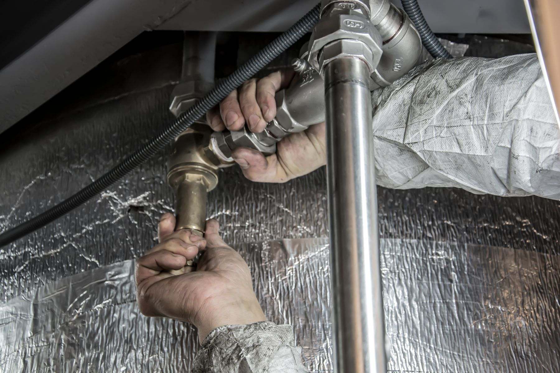Plumber tightening a pipe connection during residential water line repair in Albany OR