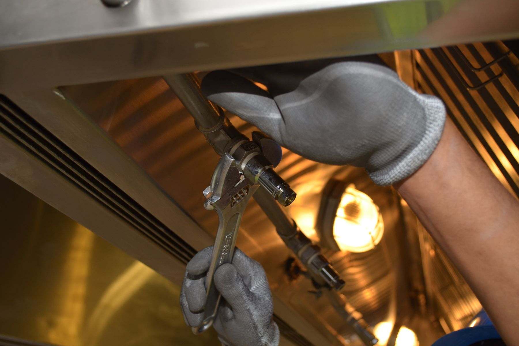 Gloved hands turning a wrench on a supply pipe during residential water line repair in Lebanon Oregon