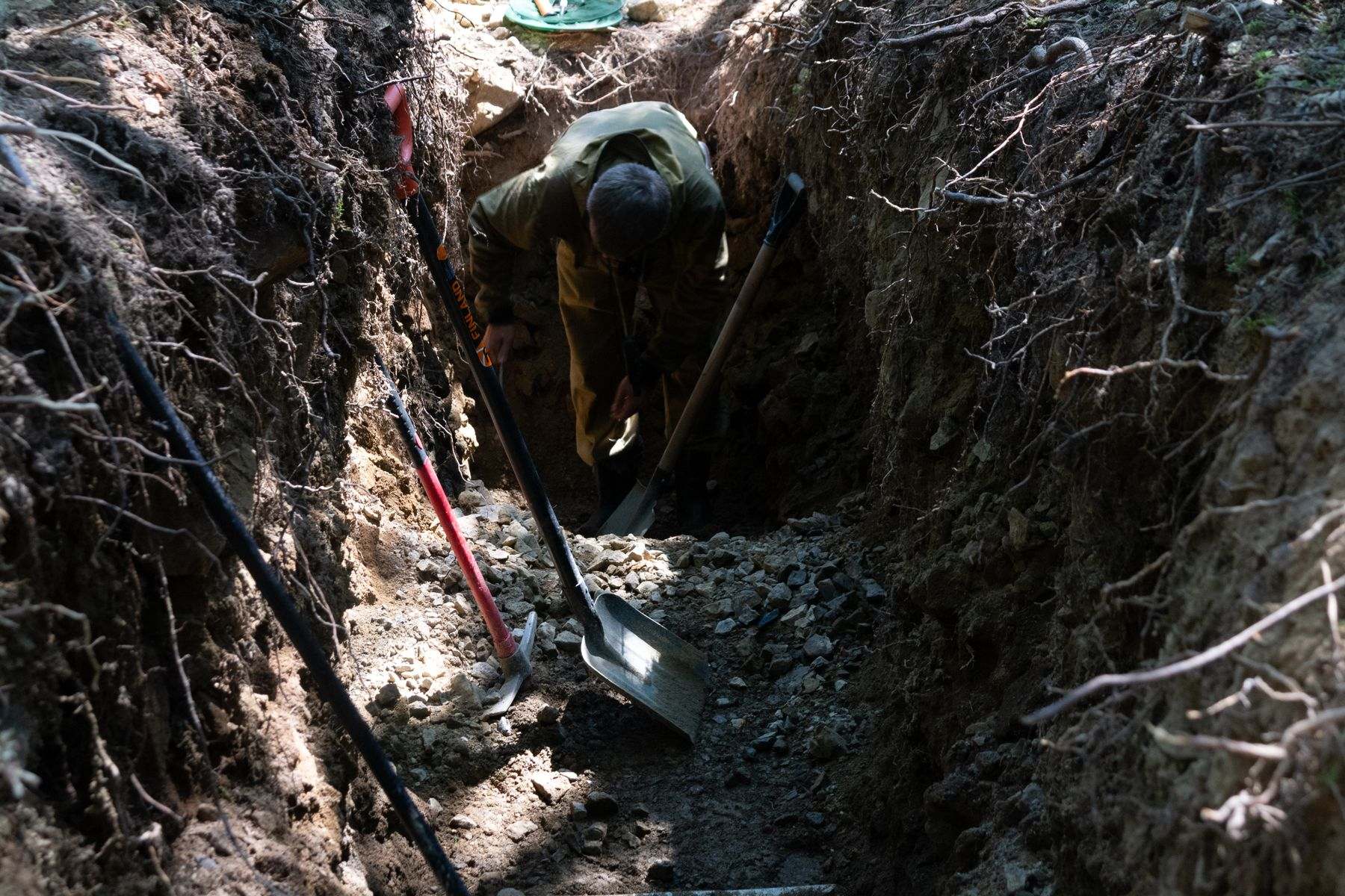 Water line installation Albany OR: a narrow trench being dug by hand for a new service line