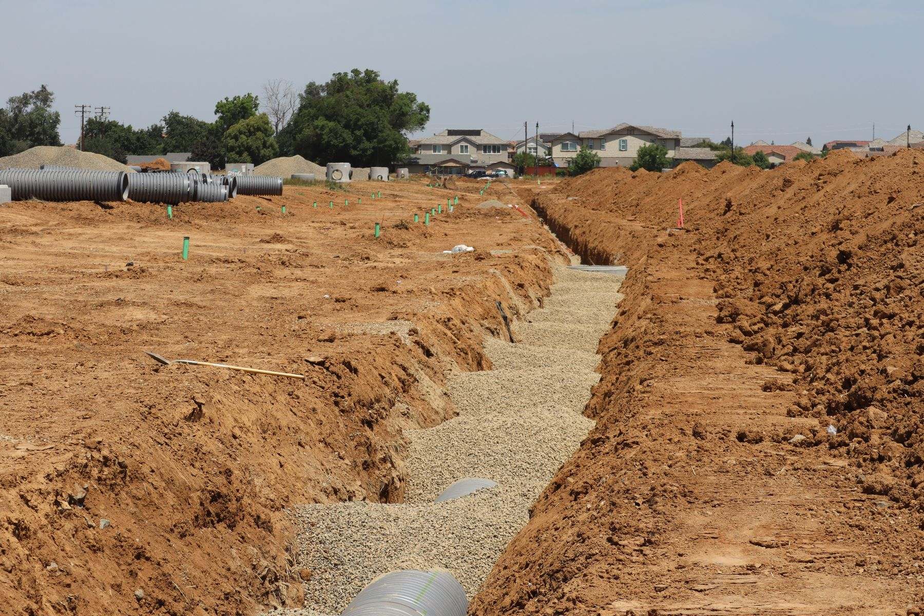 Long open trench dug across a lot, ready for a new water service line to be laid