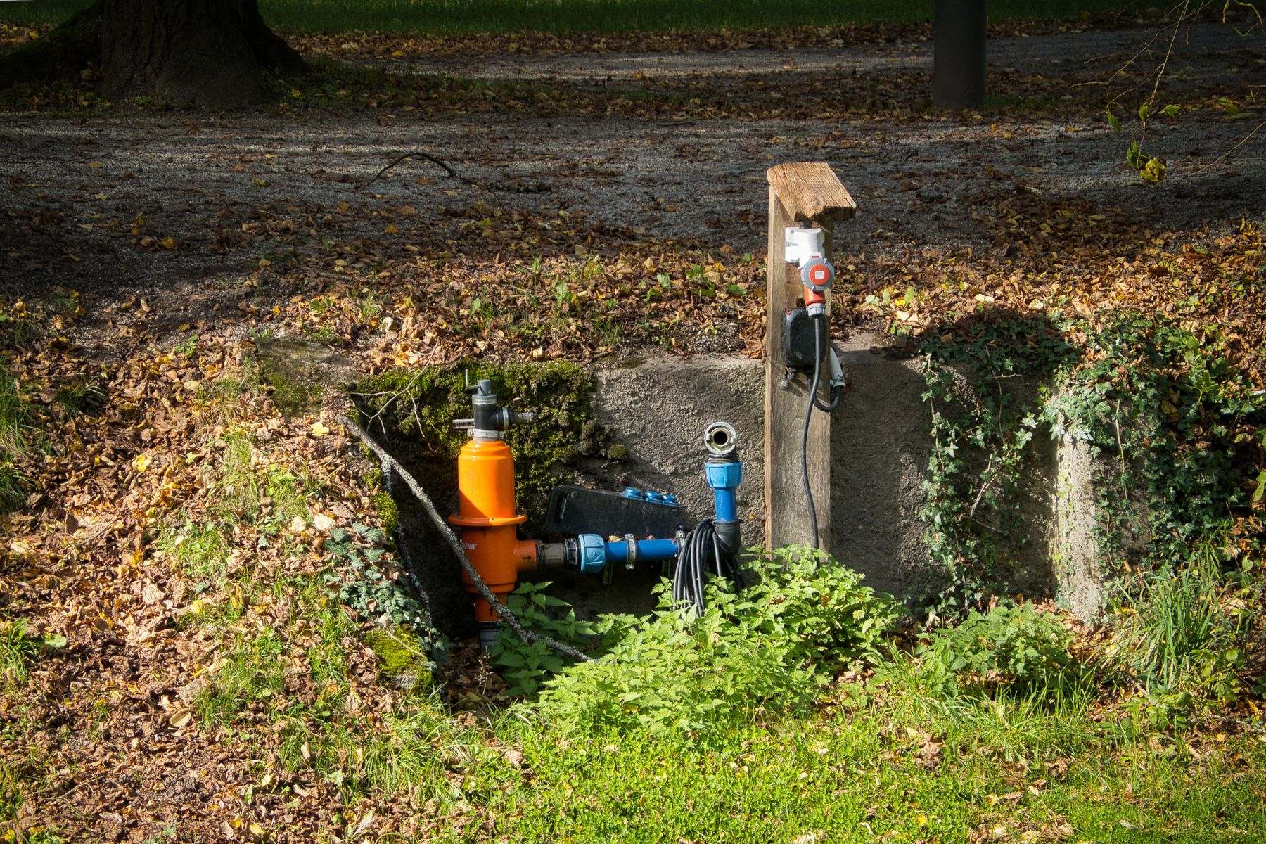 Water supply pipe, shutoff valves and a backflow assembly exposed in a yard pit during underground leak detection