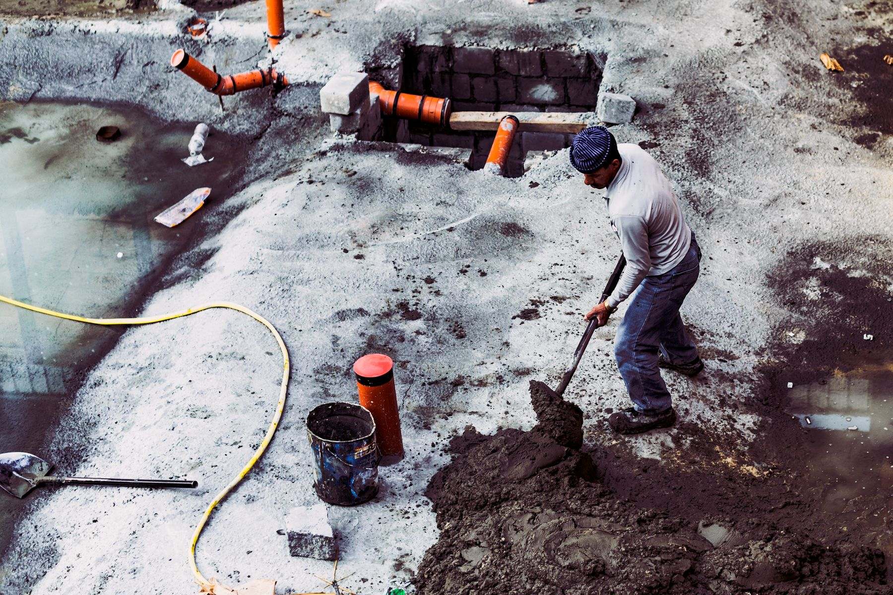 Worker digging around exposed pipe fittings where shifting soil and roots damaged a Tangent Oregon water line